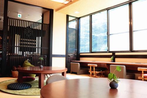 een kamer met tafels, stoelen en ramen bij Onsen Guest House Tsutaya in Hakone