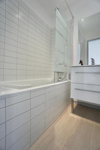 une salle de bain blanche avec une baignoire et un lavabo dans l'établissement Cabine de plage n°1 *50m de la mer*, à Ploemeur