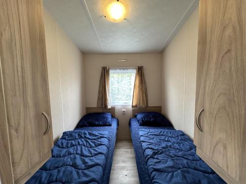 カンペルラントにあるChalet Lynn - Oosterschelde Camping in Kamperlandのベッドが2つと窓がある小さな部屋