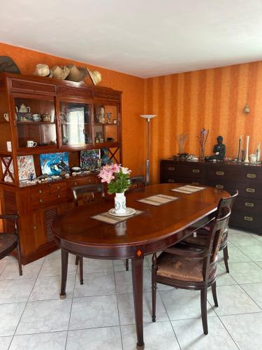 une table de salle à manger avec un vase de fleurs dessus dans l'établissement BAAN THAI ST MALO, à Saint-Malo