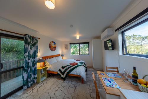 - une chambre avec un lit et une table ainsi qu'une salle à manger dans l'établissement Country Nirvana, à Pataua