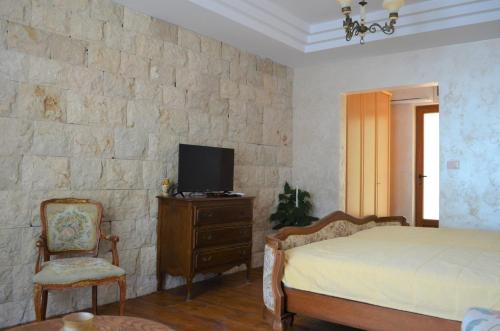 a bedroom with a bed and a tv on a stone wall at Markovic Winery and Estate apartments in Cetinje