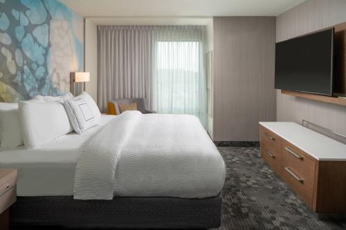 ラファイエットにあるCourtyard by Marriott Lafayette Southの大型ベッド1台、薄型テレビが備わるホテルルームです。