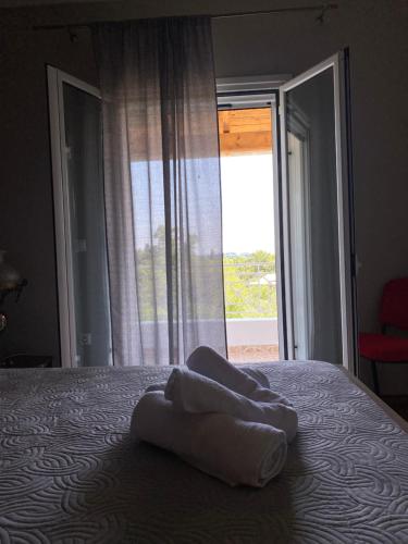 a towel on a bed in front of a window at Olive Garden House in Ágios Prokópios