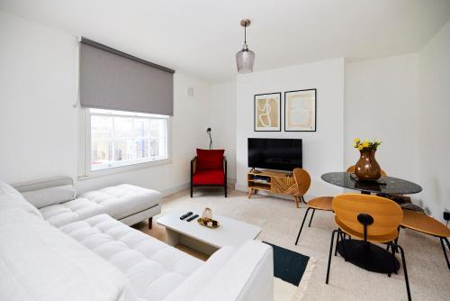 uma sala de estar com um sofá branco e uma mesa em The Clapham Getaway - Charming 1BDR Flat em Londres