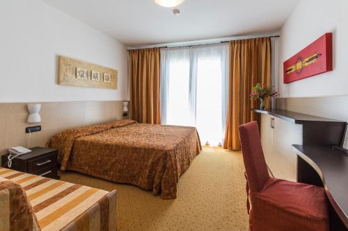um quarto de hotel com duas camas e uma janela em Hotel Olympus em Caorle