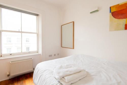 a white bedroom with a bed with towels on it at London Central Studio in London