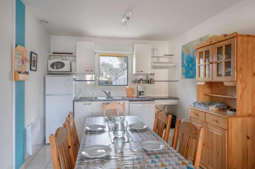 une cuisine avec une table et des chaises et une cuisine avec des appareils blancs dans l'établissement Maison confortable et familiale pour 6 personnes, à Sarzeau