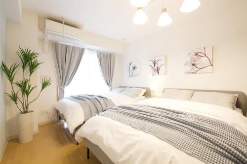2 camas en un dormitorio blanco con una maceta en Generous Forest 201, en Tokio