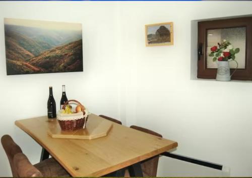 una mesa de comedor con una cesta de botellas de vino en Casa el Tejo, en San Cristóbal de Valdueza