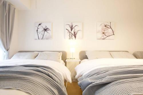 two beds in a bedroom with paintings on the wall at Generous Forest 201 in Tokyo