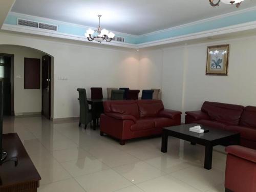 a living room with a red couch and a table at Alzebara 2 Apartment in Manama