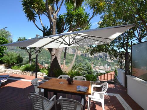 einen Tisch und Stühle unter einem Sonnenschirm auf einer Terrasse in der Unterkunft Belvilla by OYO Ventimiglia in Ventimiglia