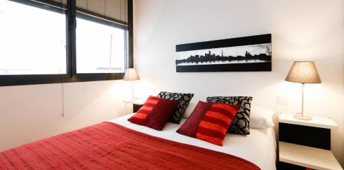 Precioso apartamento en Calle Iriarte في مدريد: غرفة نوم بسرير ومخدات حمراء