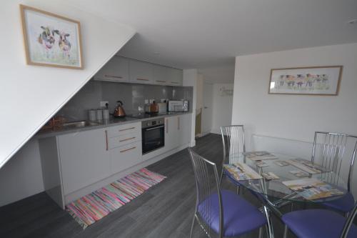 a kitchen with a table and chairs and a kitchen with a staircase at St Duthus Hotel Apartment in Tain