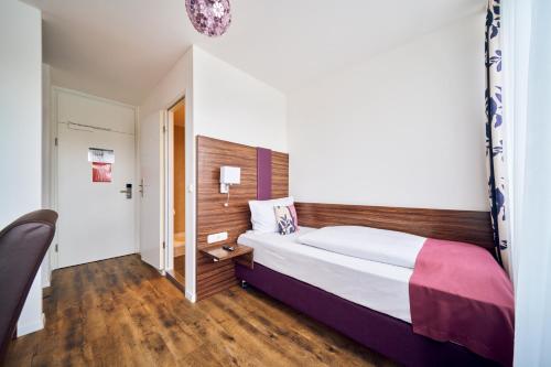 a bedroom with a large bed and wooden floors at ARTHOTEL Haar in Haar