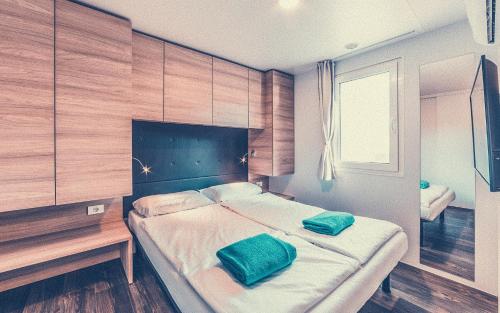 1 dormitorio con 1 cama con 2 almohadas verdes en Bungalows Tenuta Primero, en Grado