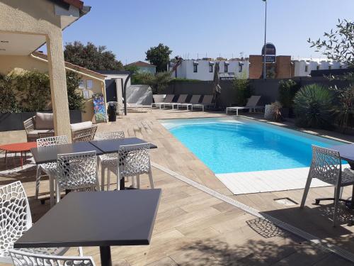 - une piscine avec des tables et des chaises à côté d'une maison dans l'établissement Kyriad Carcassonne - Aéroport, à Carcassonne