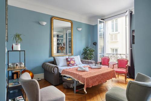 a living room with a couch and a mirror at Apartment place de l'Etoile By Studio prestige in Paris