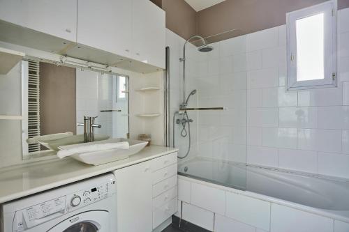 a white bathroom with a sink and a washing machine at Apartment place de l'Etoile By Studio prestige in Paris