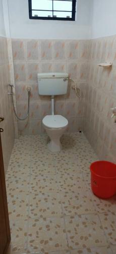 a bathroom with a toilet and a bucket at Happy Homes , Thekkady in Vandiperiyār