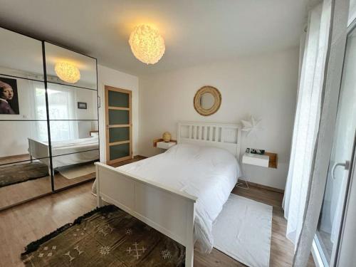 une chambre avec un lit blanc et un grand miroir dans l'établissement Le Galilée - Jardin privatif, à La Rochelle