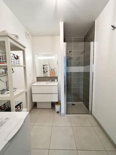 une salle de bain blanche avec une douche et un lavabo dans l'établissement Le Galilée - Jardin privatif, à La Rochelle