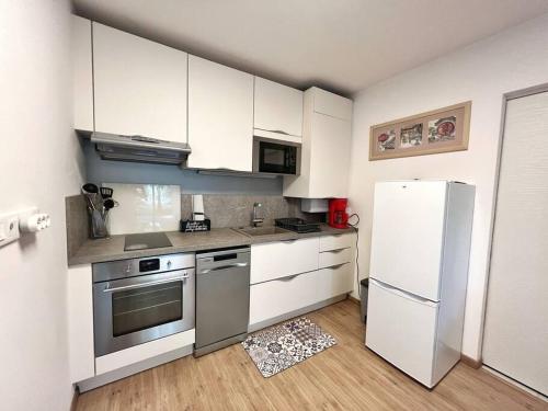 une cuisine avec des armoires blanches et un réfrigérateur blanc dans l'établissement Le Galilée - Jardin privatif, à La Rochelle