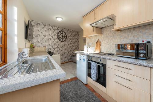 a kitchen with a sink and a microwave at Cosy Cottage in Historic Lincoln in Lincolnshire