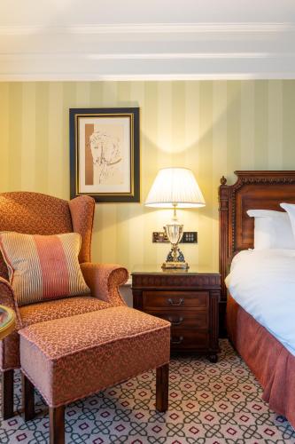 a bedroom with a bed and a chair and a lamp at Powerscourt Hotel, Autograph Collection in Enniskerry