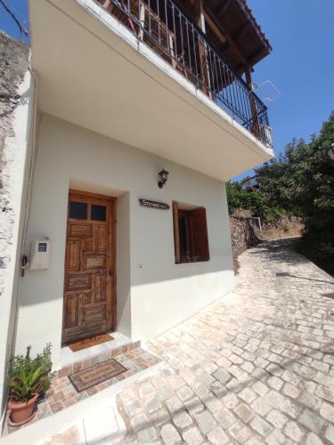 Casa blanca con puerta de madera y balcón en Stefanis traditional house - Kampos, en Kámbos