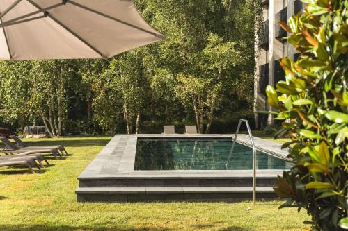 uma piscina com um guarda-sol ao lado de um edifício em Balneario Font Vella- Adults Only em Sant Hilari Sacalm