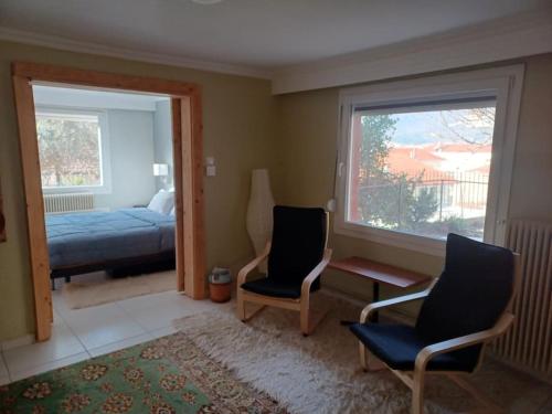 - une chambre avec deux chaises, un lit et une fenêtre dans l'établissement Άνετη κατοικία με κήπο, à Kastoria