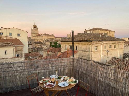 une table avec des assiettes de nourriture sur un balcon dans l'établissement Appartement lumineux, terrasse, centre historique, à Arles