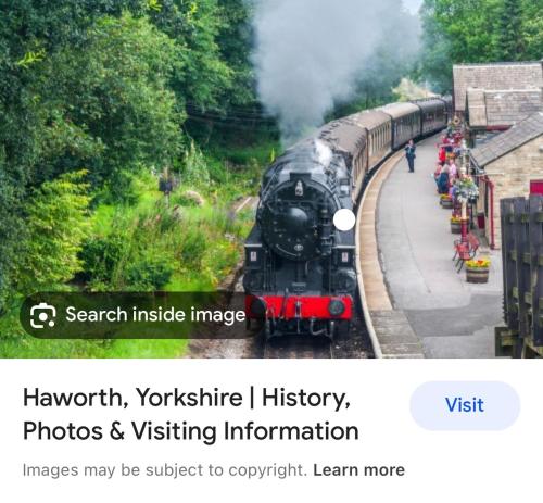 a steam train pulling into a train station with passengers at Contemporary apartment Great Location with private carpark in Keighley