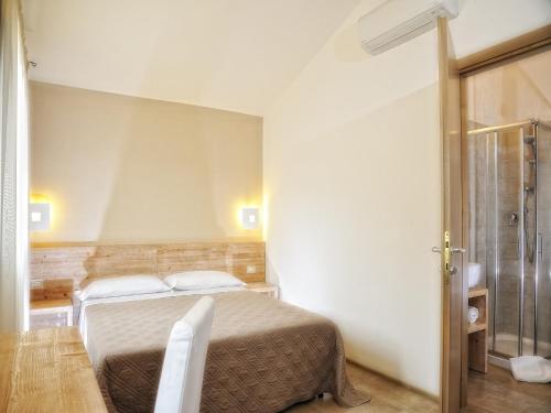 1 dormitorio con cama, mesa y puerta de cristal en B&B Le Cale, en Santa Maria Navarrese