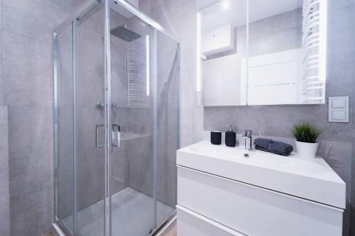 a bathroom with a glass shower and a sink at City Center - 3 Rooms - New Building - Private Parking Place - Garage in Wrocław