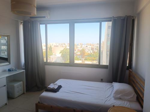 a bedroom with a bed and a large window at Heart of the City in Limassol