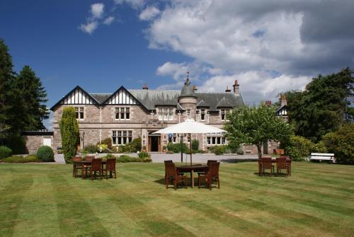 a large house with a table and chairs in the yard at Ramnee Hotel in Forres