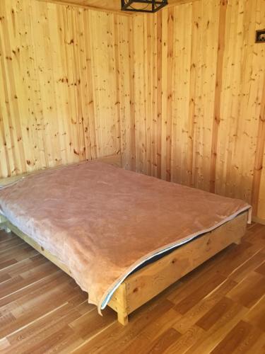 Bett in einem Zimmer mit einer Holzwand in der Unterkunft Sunset Krikhi in Ambrolauri