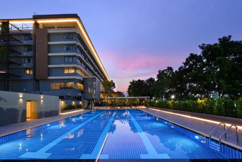 a swimming pool in front of a building at night at Tinidee Hotel Bangkok Golf Club in Pathum Thani