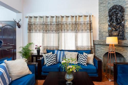 a living room with blue couches and a window at Poetry by the Hills - House Of Hive, Ramgarh, Mukteshwar, Nainital in Rāmgarh