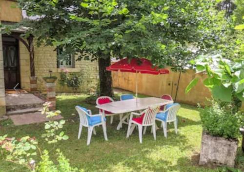 - une table et des chaises dans une cour avec un parasol dans l'établissement la Montjoie, à Montignac