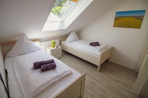 1 dormitorio en el ático con 2 camas y ventana en Grashaus Leevke, en Krummhörn