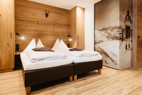 two beds in a room with a wooden wall at Embacher Sporthotel in Embach