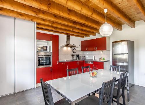 une cuisine avec une table blanche et des placards rouges dans l'établissement Domaine Joseph LAFARGE Wine Resort WineMaker House La maison du Vigneron, à Lugny