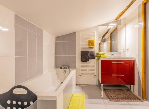 a bathroom with a bath tub and a red cabinet at Domaine Joseph LAFARGE Wine Resort WineMaker House La maison du Vigneron in Lugny