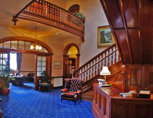 a lobby with a staircase and a chair in a room at Ramnee Hotel in Forres