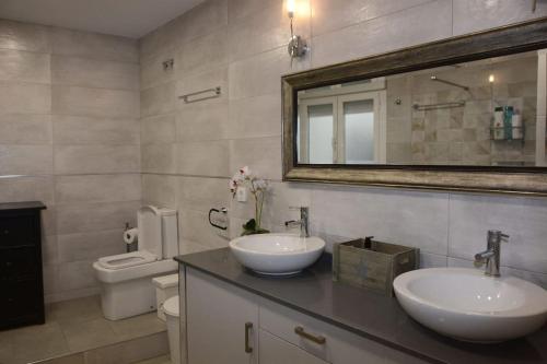 a bathroom with two sinks and a mirror and a toilet at Casa Macarena Espectacular Plaza Mayor in Ciudad-Rodrigo