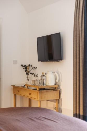 a tv on a wall with a wooden table with a table sidx sidx at Isle of Raasay Distillery in Raasay